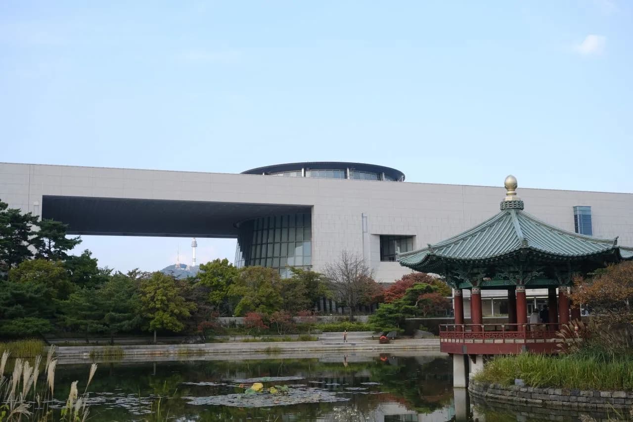 The long stone facade of the National Museum of Korea with a traditional pavilion and reflecting pond in front