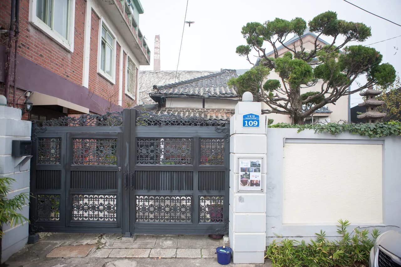 A cafe set inside a restored traditional Korean building behind an ornate gate and a shaped pine