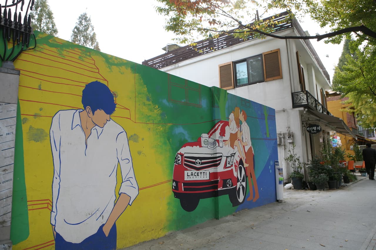 A Samcheong-dong street with a painted wall mural and low buildings on a clear day