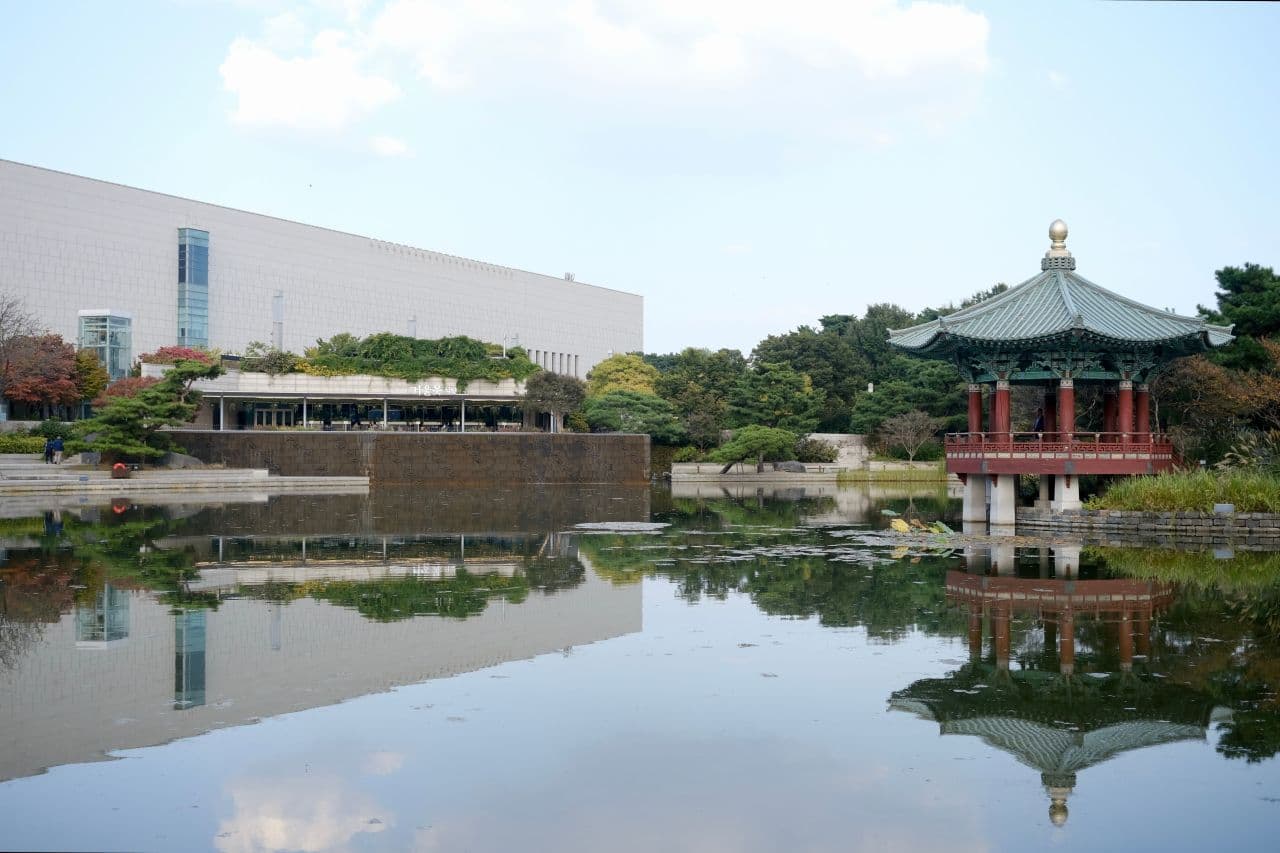 The National Museum of Korea building and a traditional pavilion reflected in its pond, Seoul