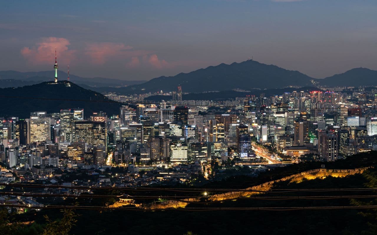 Seoul's city skyline at dusk with N Seoul Tower and mountains behind