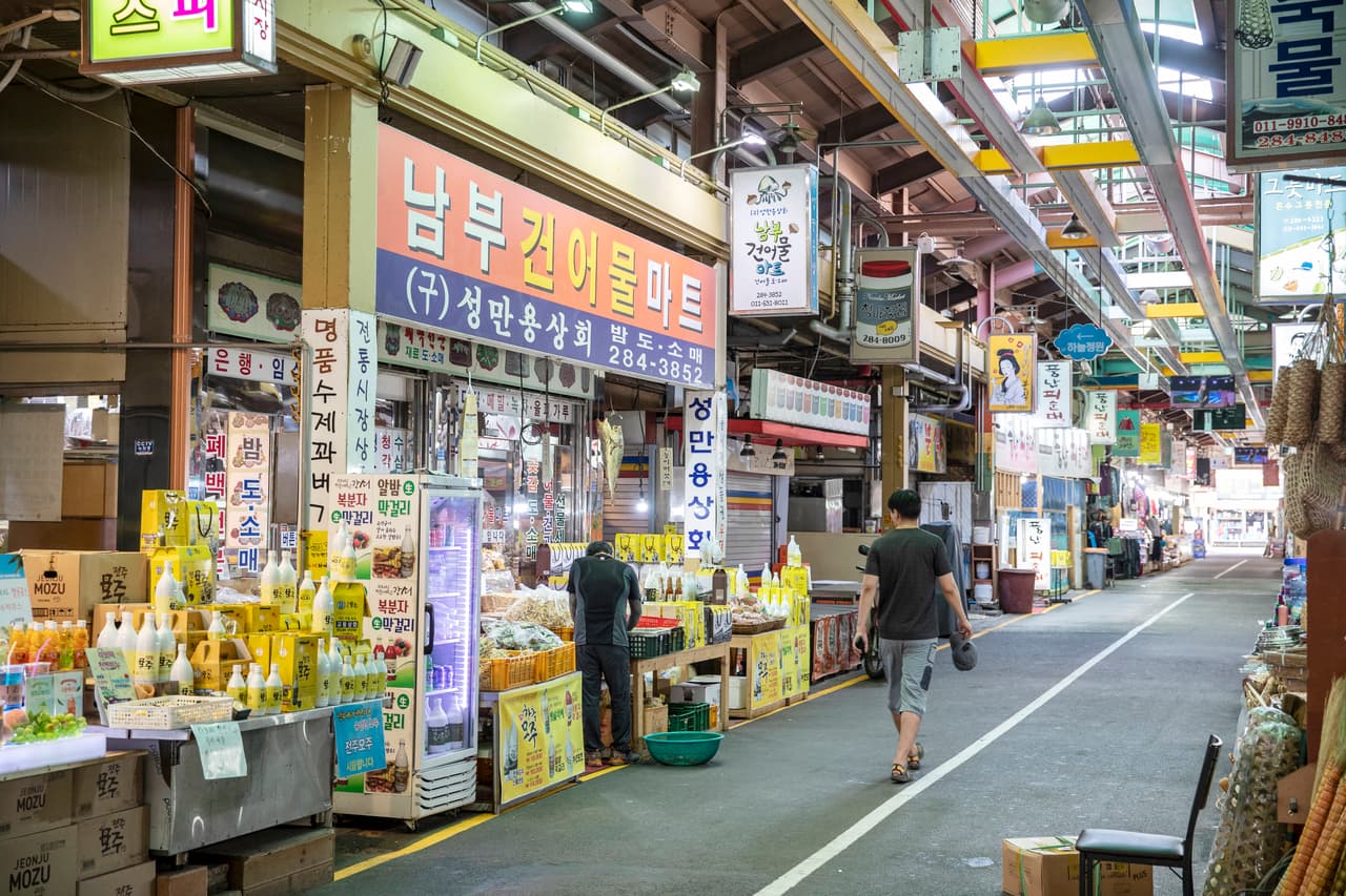 A covered aisle of stalls and small shops inside Nambu Market in Jeonju