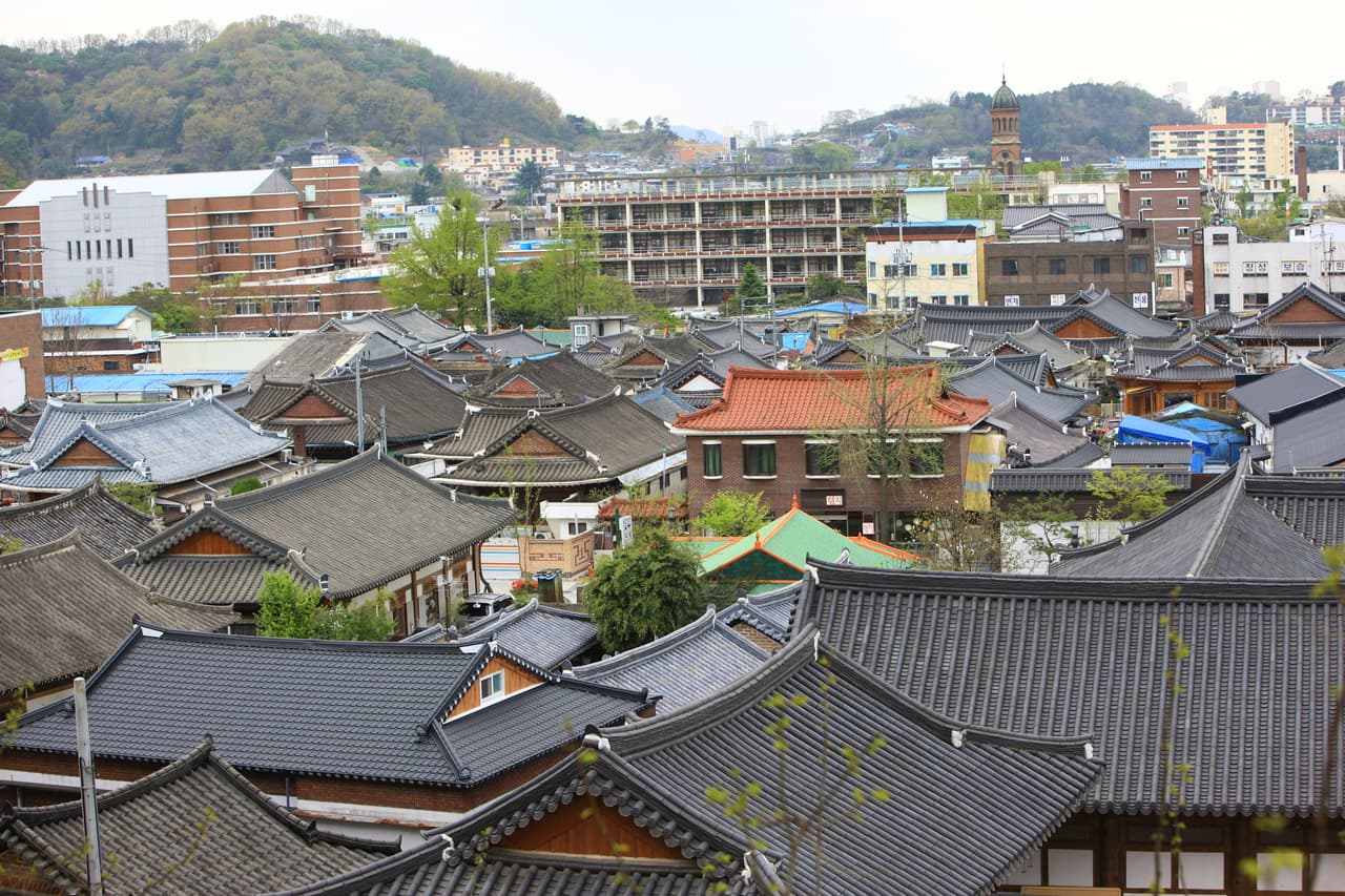 A panorama of the tiled rooftops of Jeonju Hanok Village with the city behind
