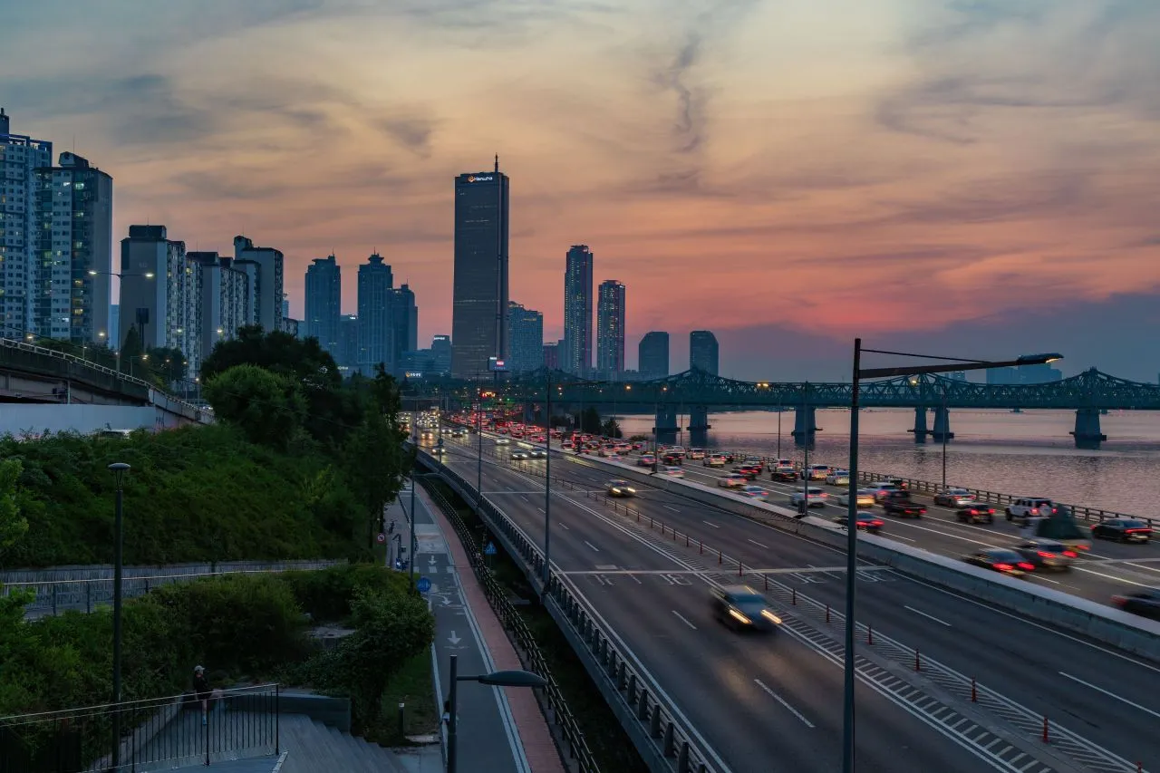 A summer sunset over the Han River with the city skyline and light trails on the riverside expressway, Seoul