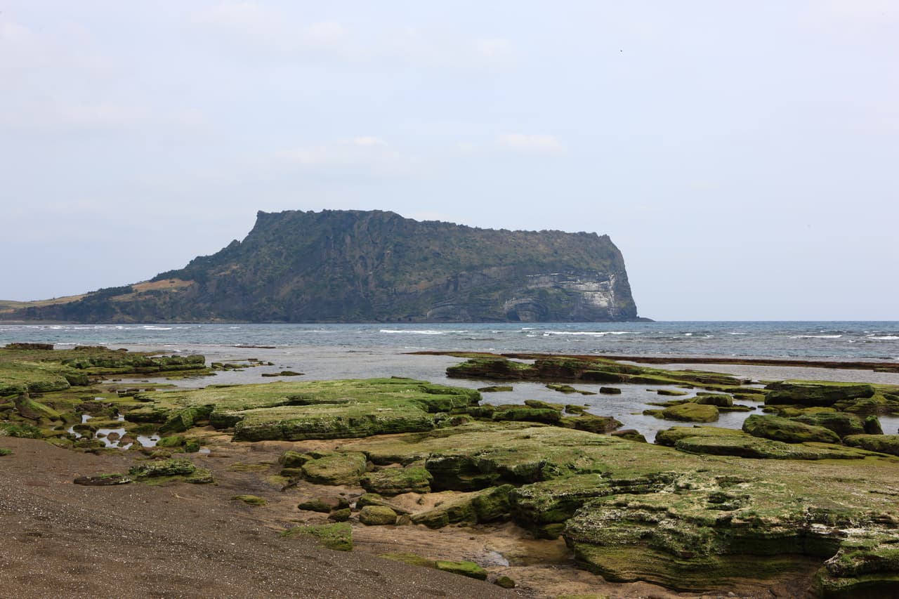 Seongsan Ilchulbong (Sunrise Peak) rising above the volcanic rock coast on eastern Jeju
