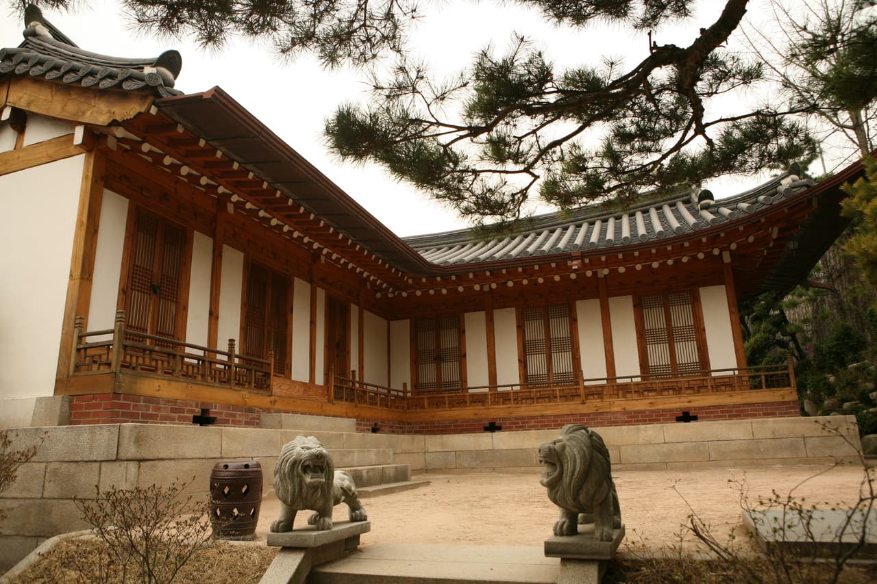 A traditional hanok with a tiled roof and stone guardian statues in the Bukchon area, Seoul