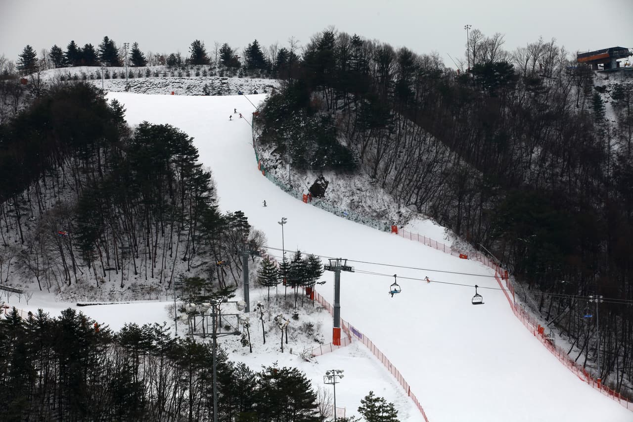 A snow-covered ski slope with chairlifts winding between wooded hills near Seoul