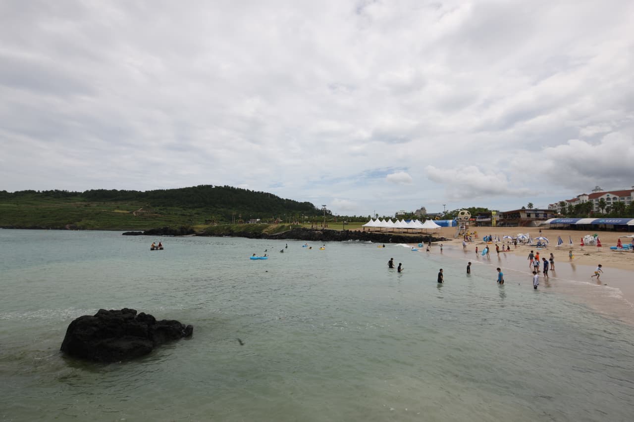 Hamdeok Beach's shallow turquoise water with Seowubong hill behind it on Jeju