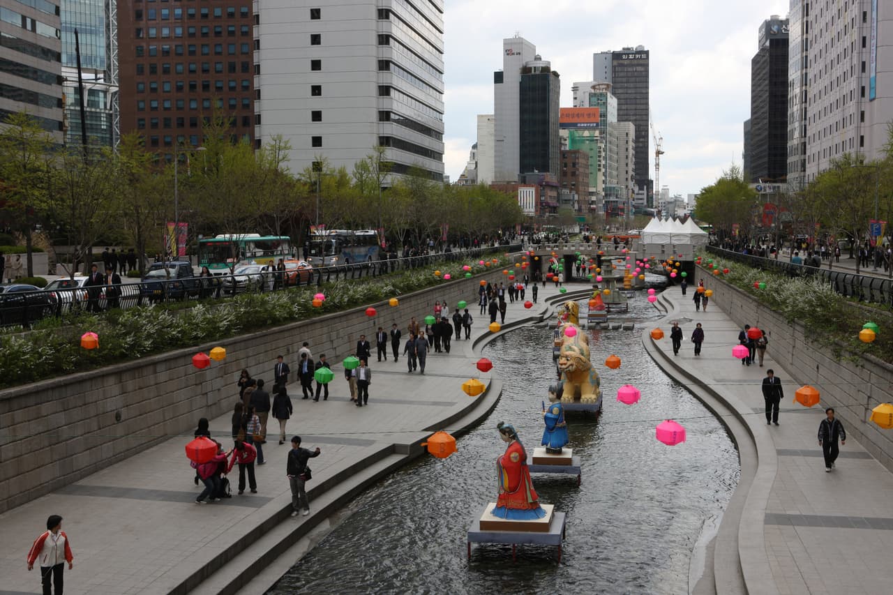 A sunken stream walkway with stepping stones and bridges between downtown Seoul buildings