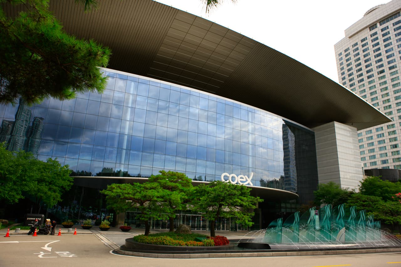 The glass-fronted COEX convention center in Gangnam with a fountain and pine trees