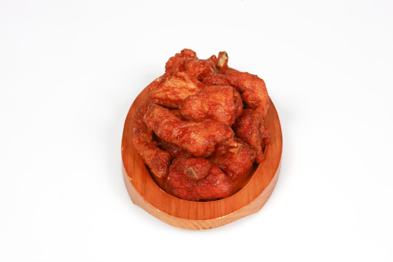 A wooden dish of yangnyeom — Korean fried chicken in a glossy sweet-spicy red sauce
