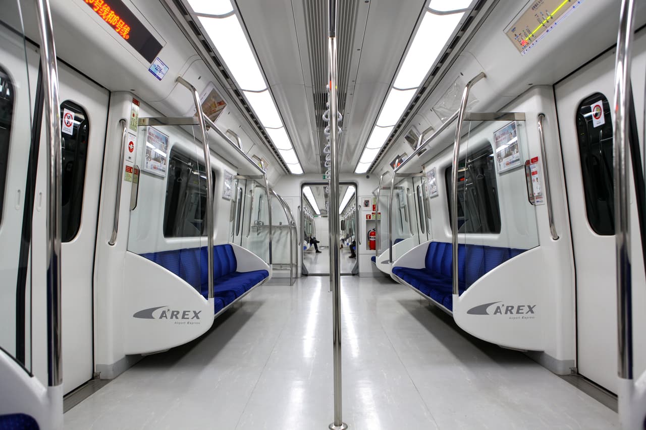 A symmetrical view down the aisle of an empty modern train car with rows of seats