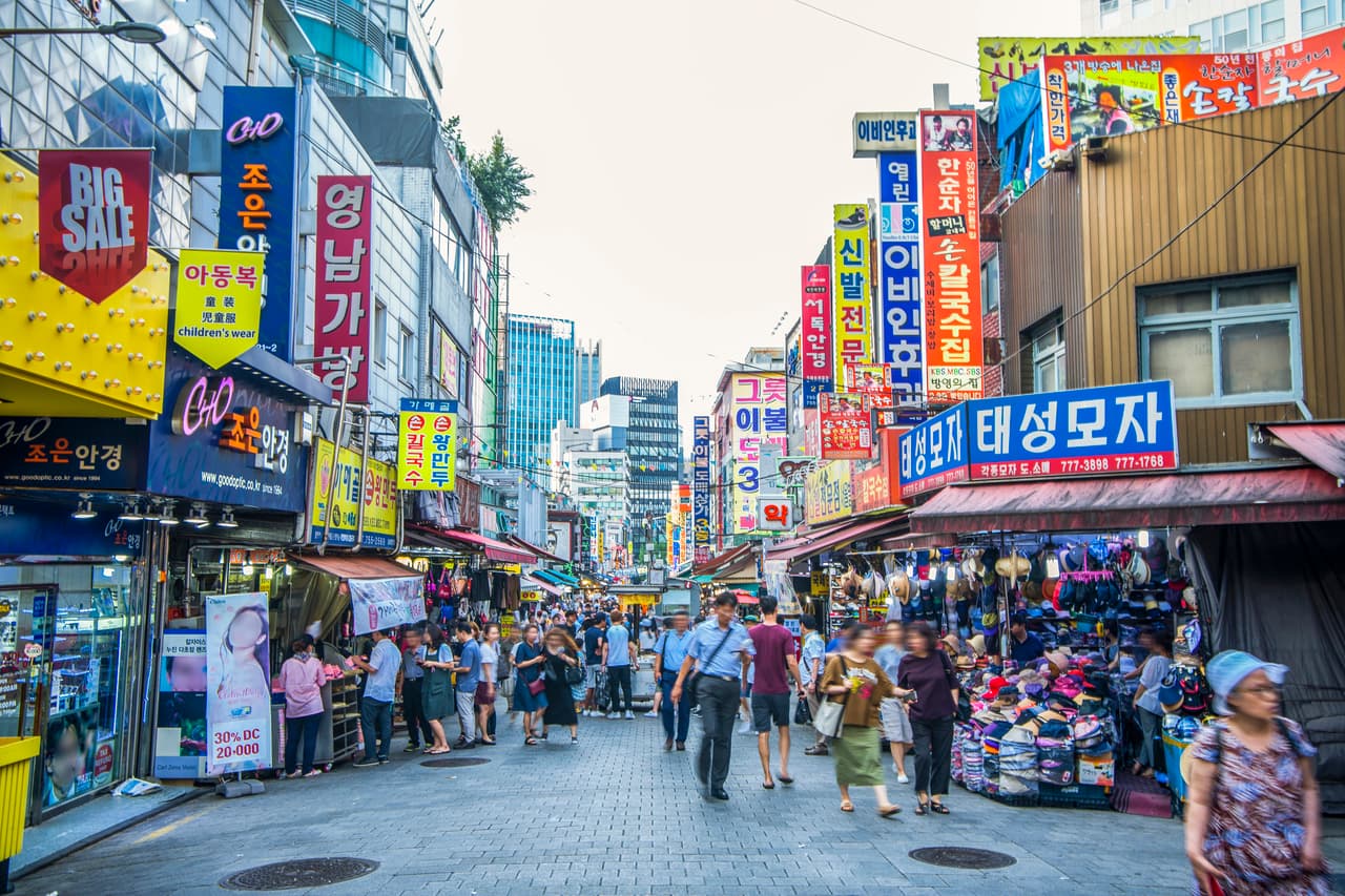 A busy traditional market alley at Namdaemun Market in Seoul with shop signs and stalls