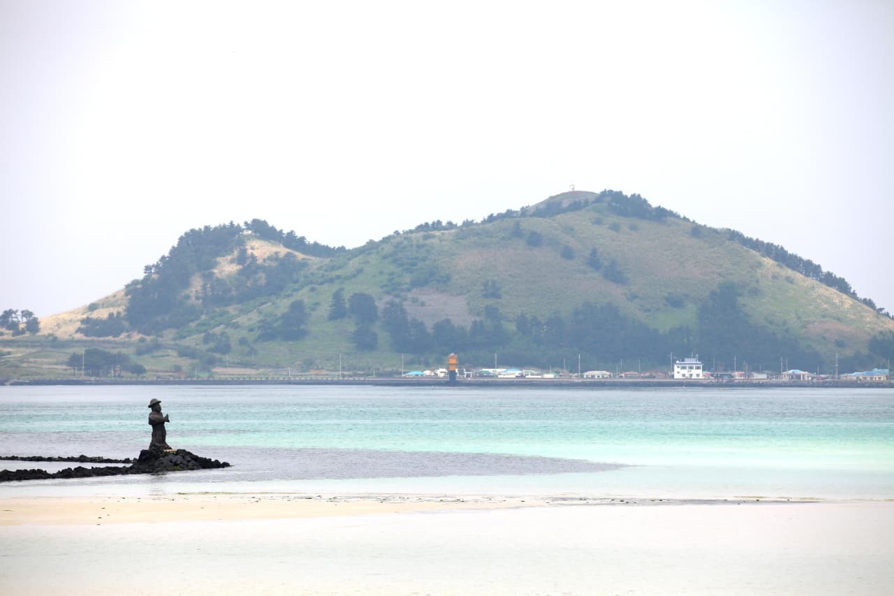 Geumneung Beach's exposed sandbar and turquoise tidal channel at low tide on Jeju