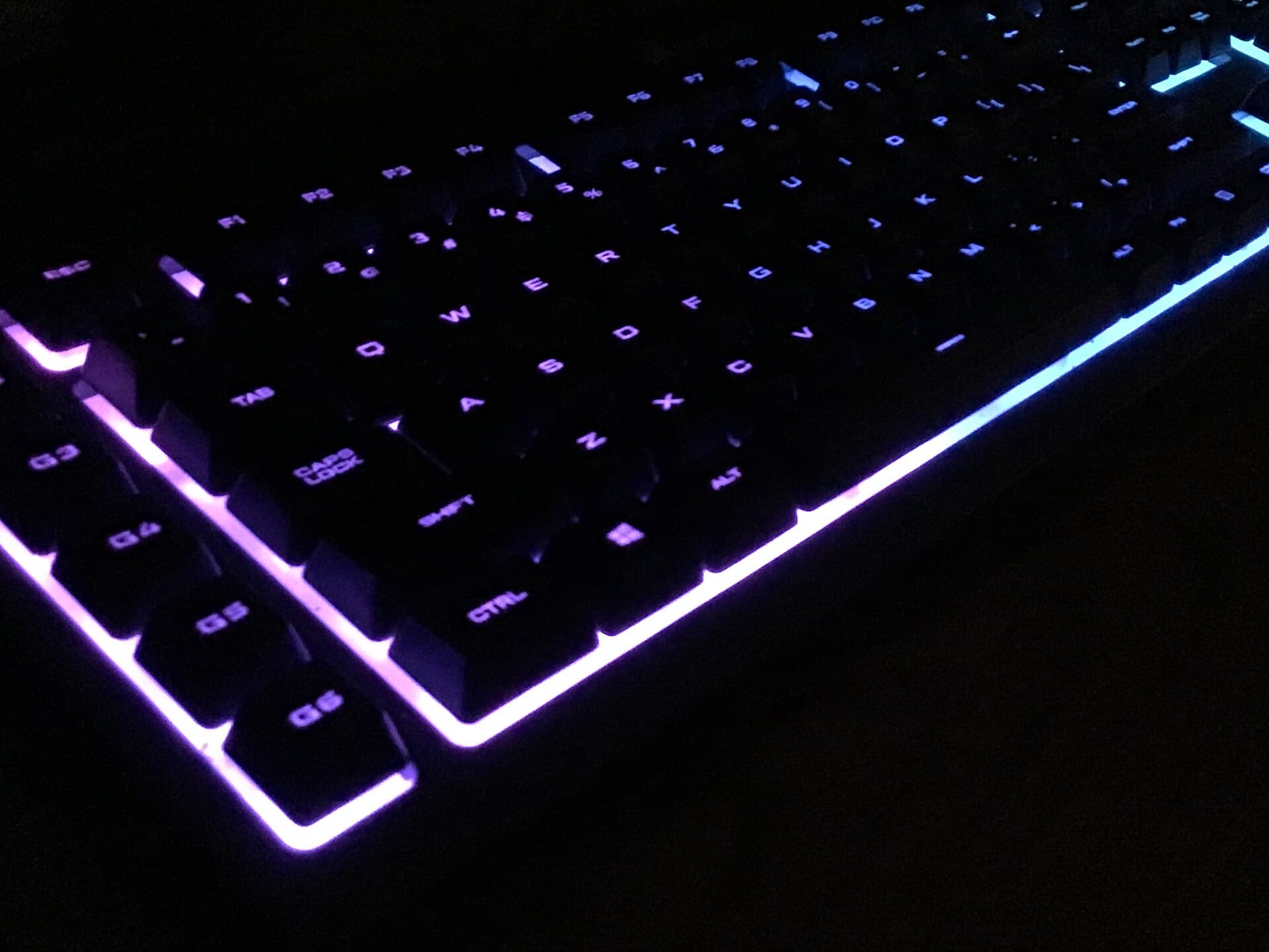 A backlit mechanical keyboard glowing in a dark room