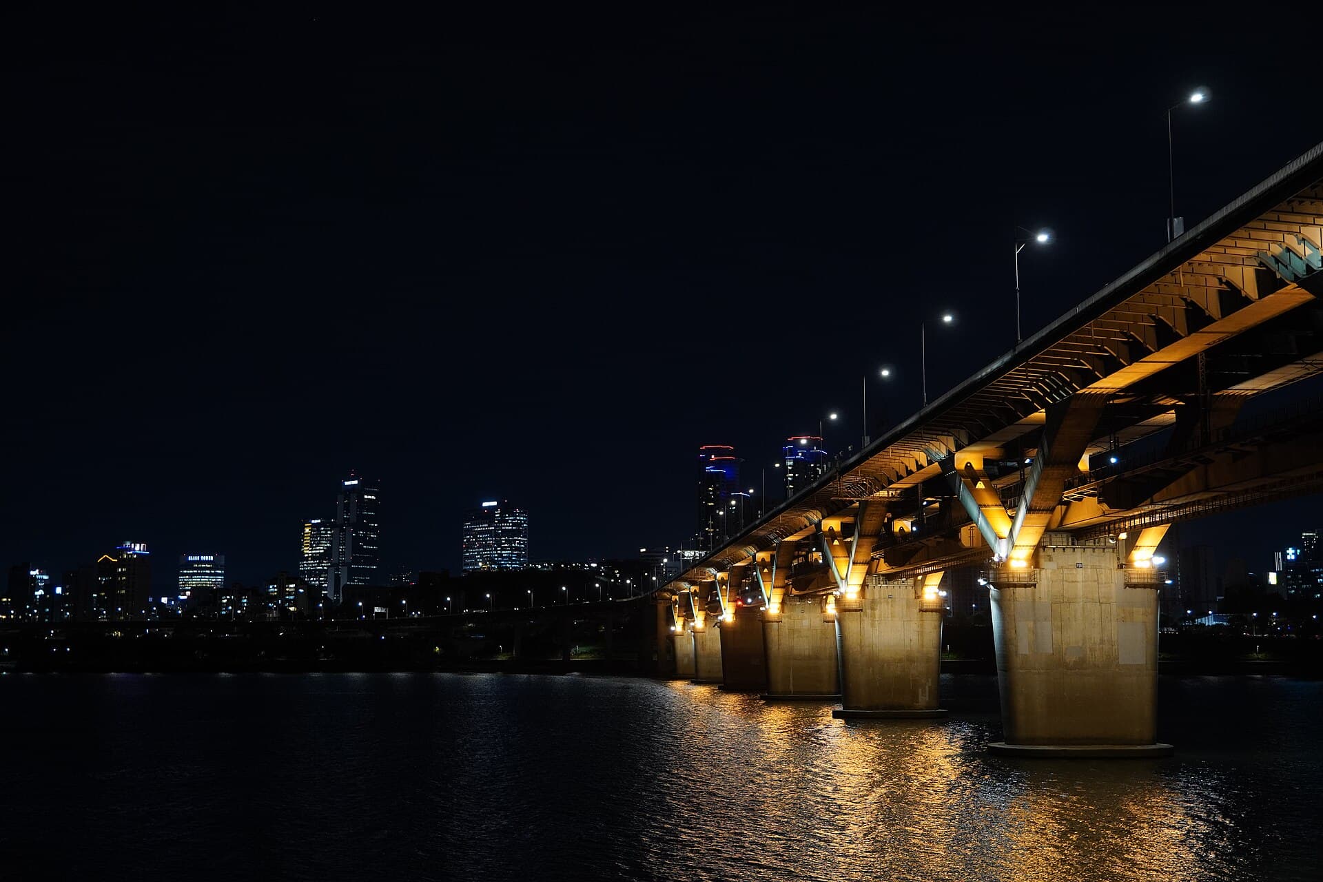 A lit bridge over the Han River seen at night from Ttukseom Hangang Park