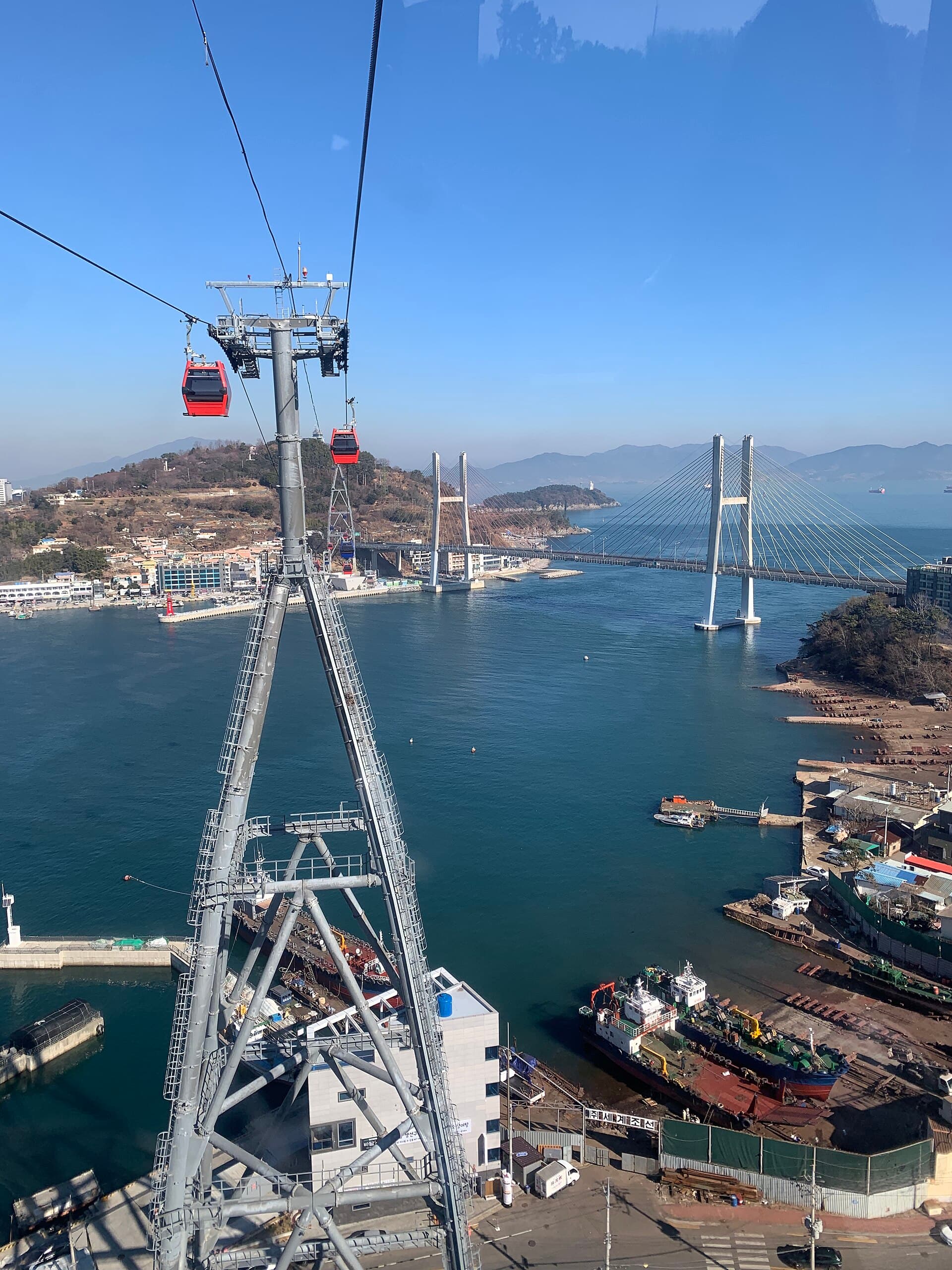 Yeosu Maritime Cable Car cabins crossing the sea with Dolsan Bridge in the background
