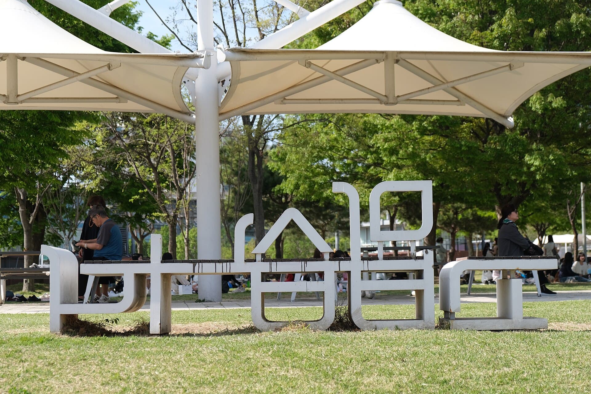 A Korean-lettering park sign and shade canopies on the lawn at Ttukseom Hangang Park in Seoul