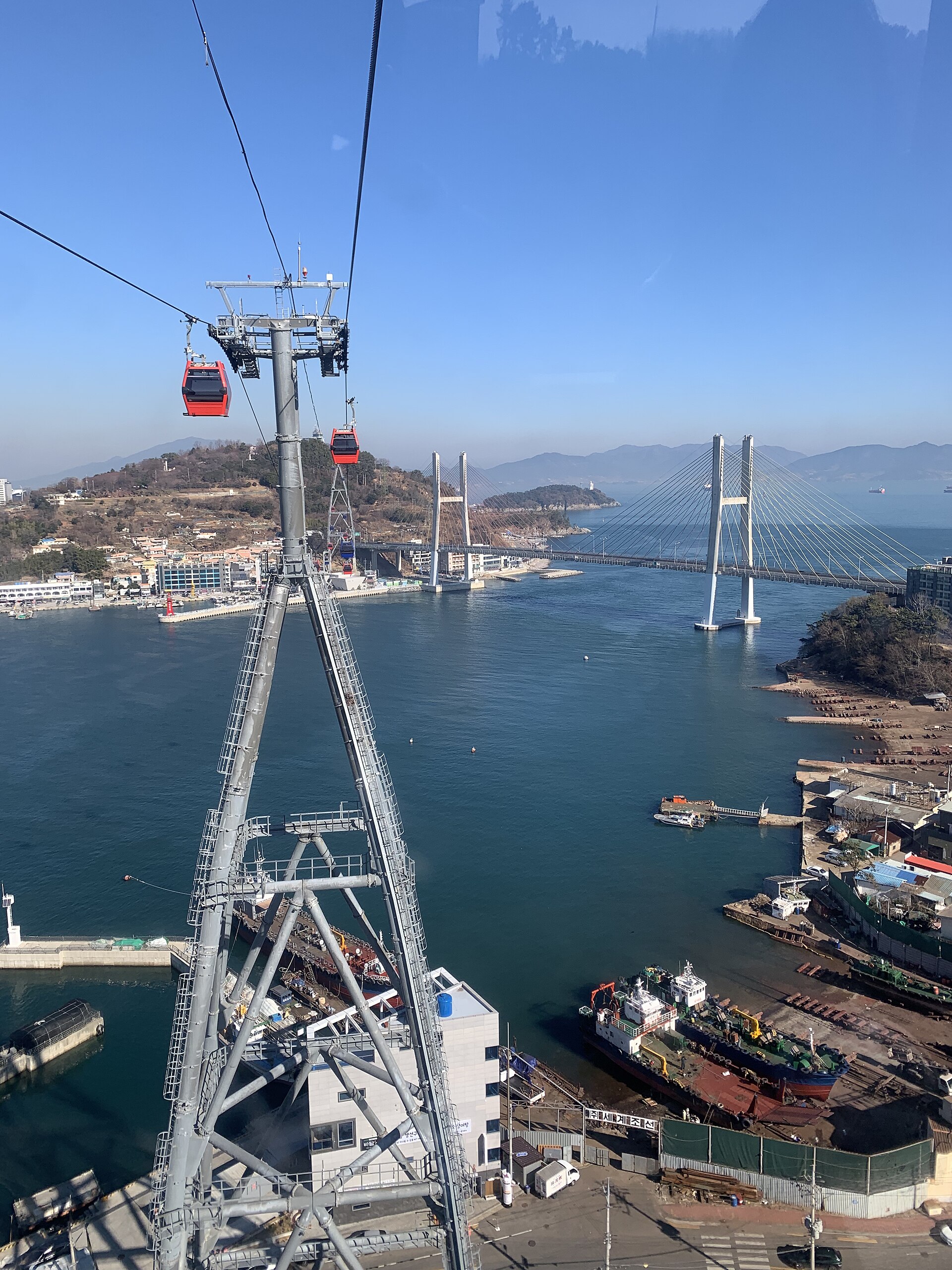 Yeosu Maritime Cable Car cabins crossing the sea with Dolsan Bridge behind