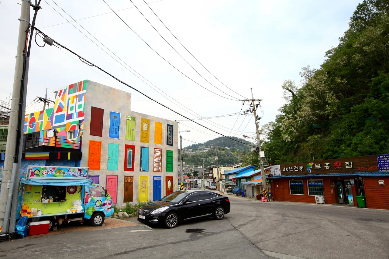Colorful mural walls along Nongoldam-gil street in Donghae with visitors walking away from the camera