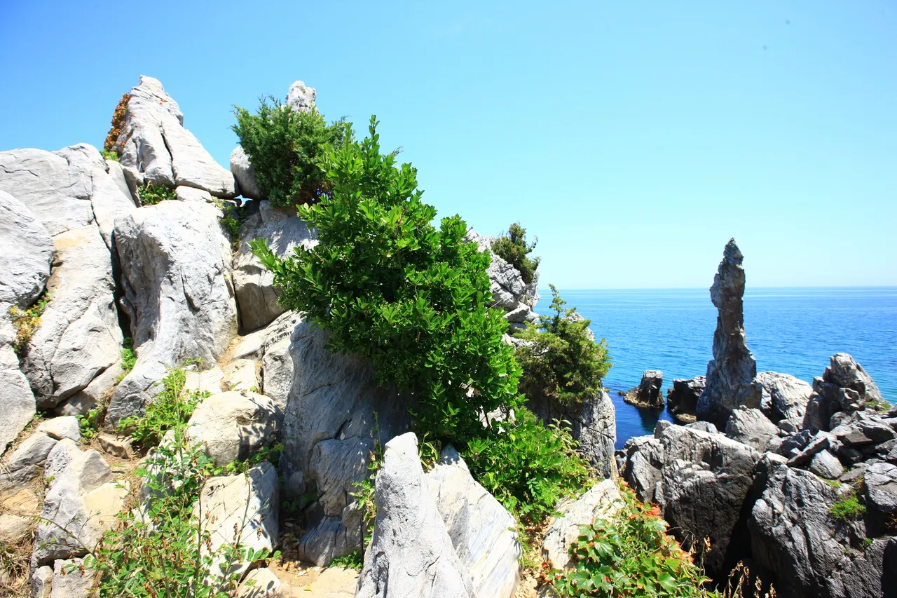 Candlestick Rock rising from the East Sea at Chuam with people in the water nearby