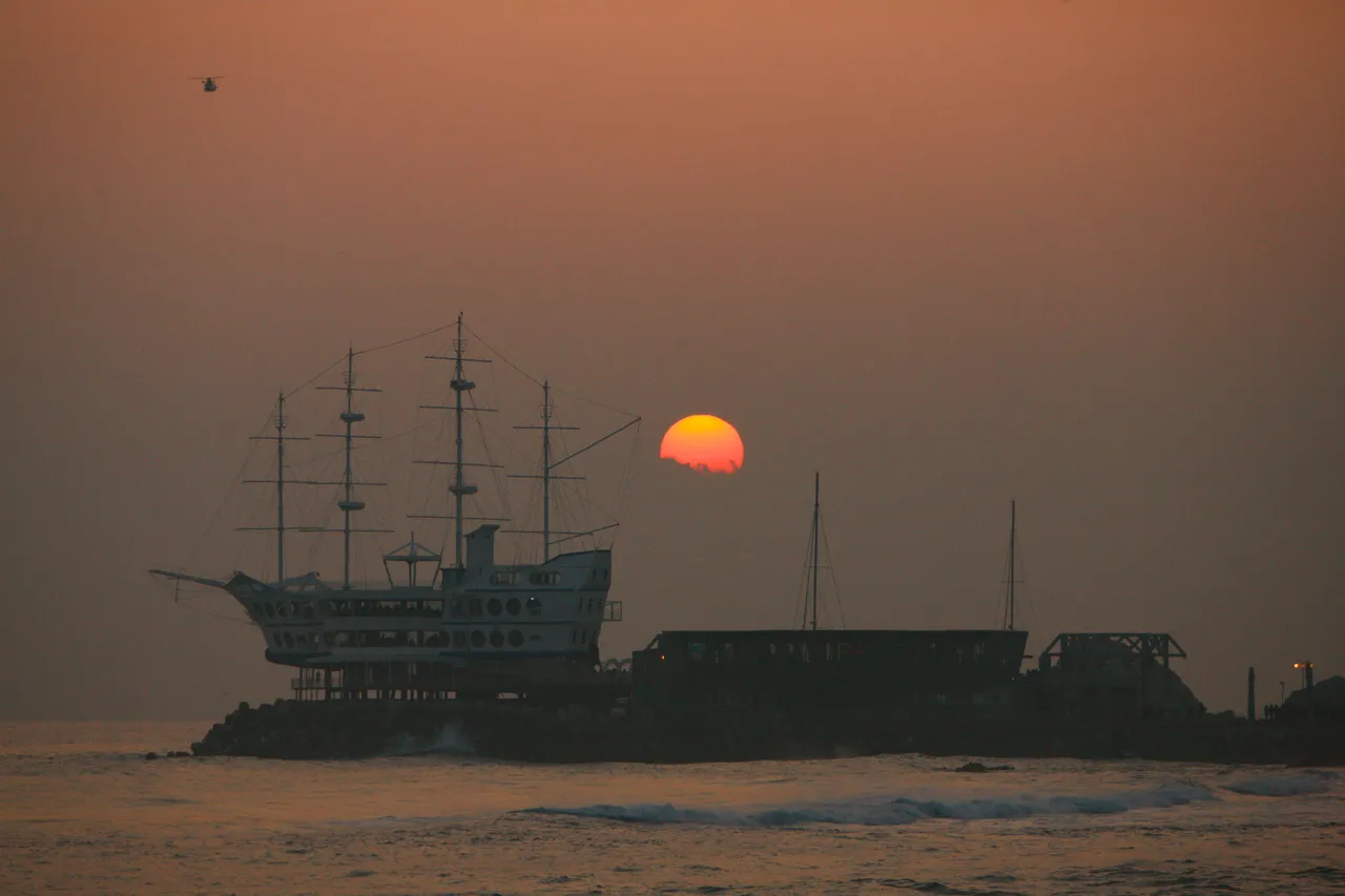 Sun rising over the sea at Jeongdongjin Beach in Gangneung, with a ship-shaped building in silhouette