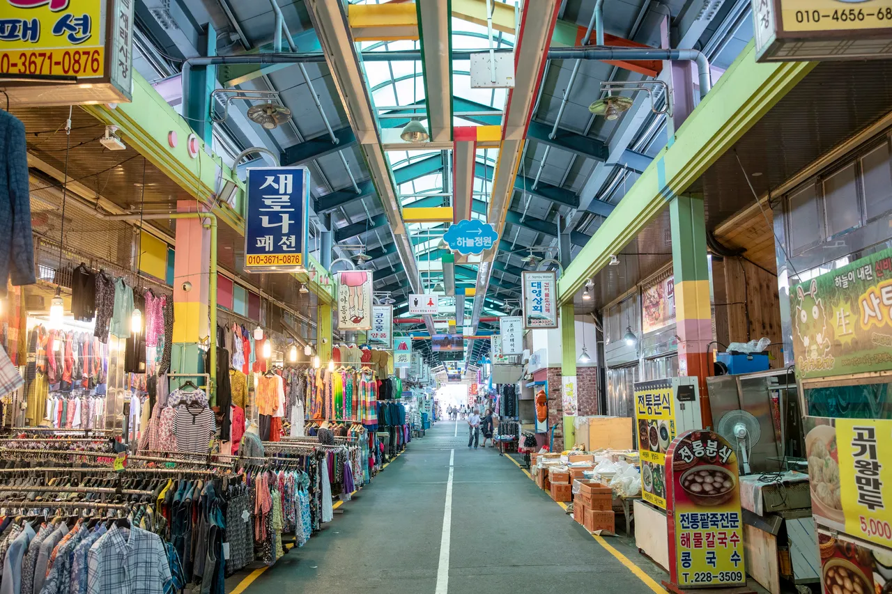 A covered lane inside Nambu Market in Jeonju with shop signs and goods on display