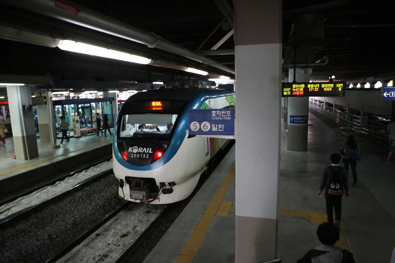 A KORAIL train at a station platform with a Seoul destination sign and a departure board