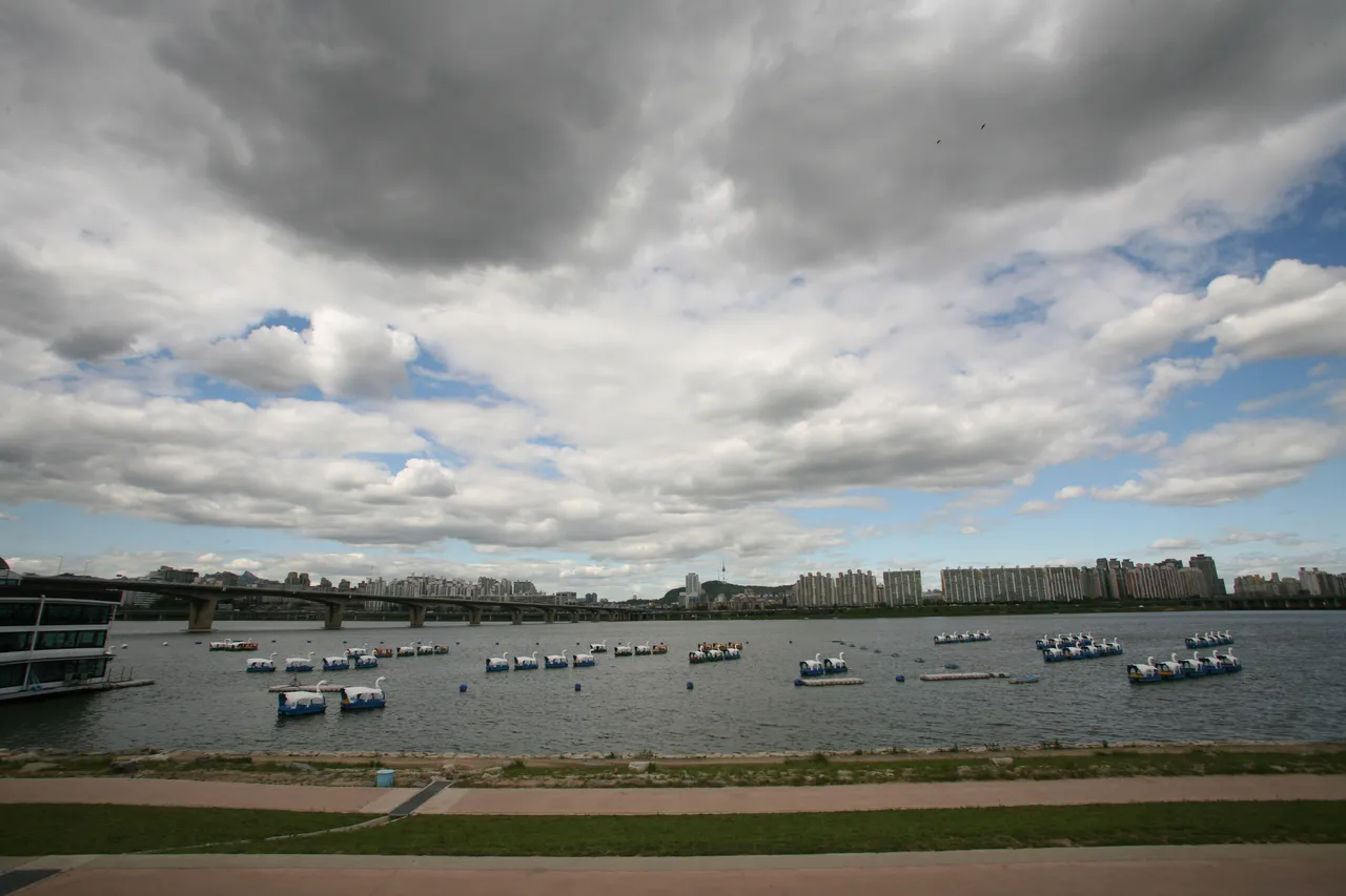 The Han River in Seoul with bridges, boats, and green riverbanks under a bright sky