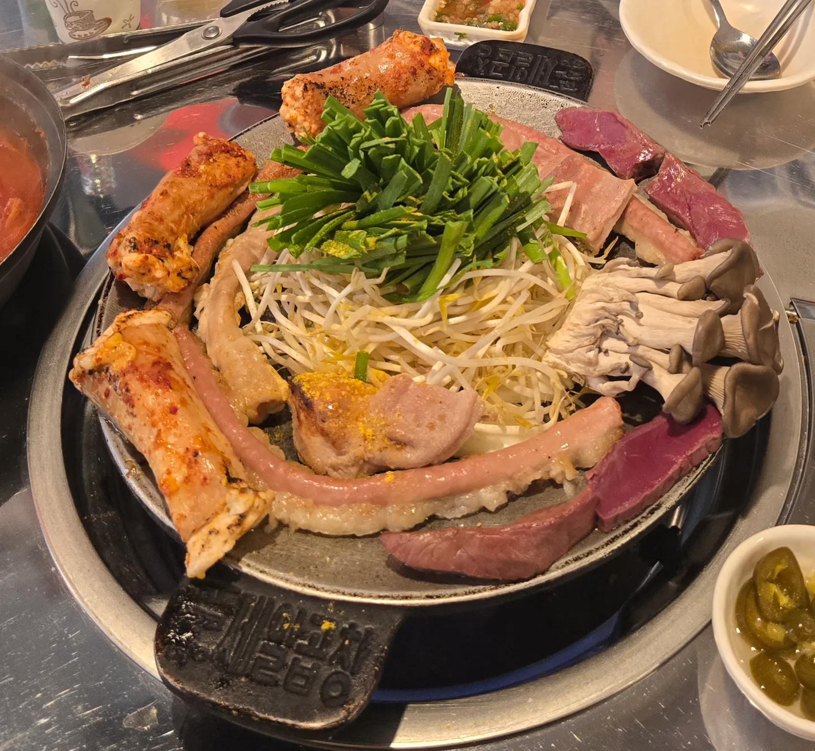 Grilled beef gopchang browning on a Korean iron plate with garlic chives and potato