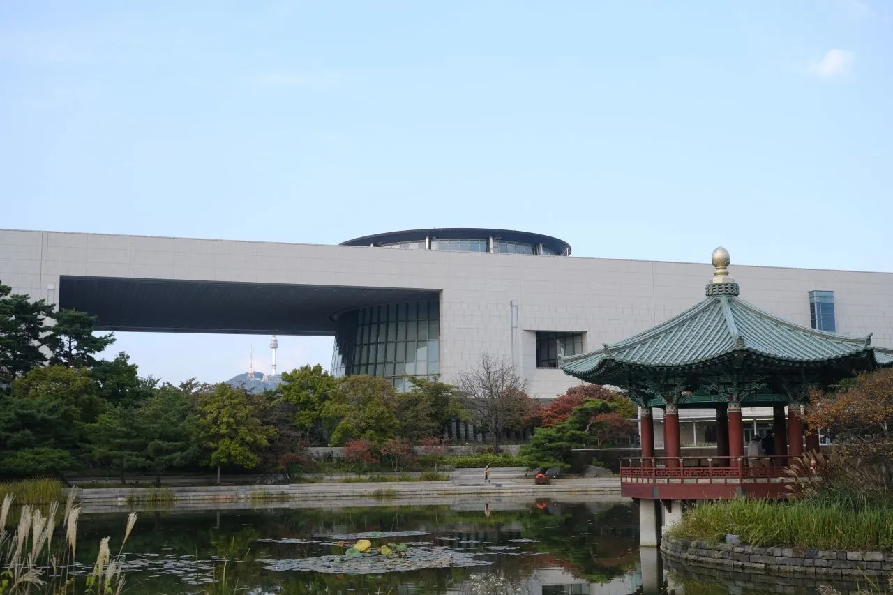 The long stone facade of the National Museum of Korea with a traditional pavilion and reflecting pond in front