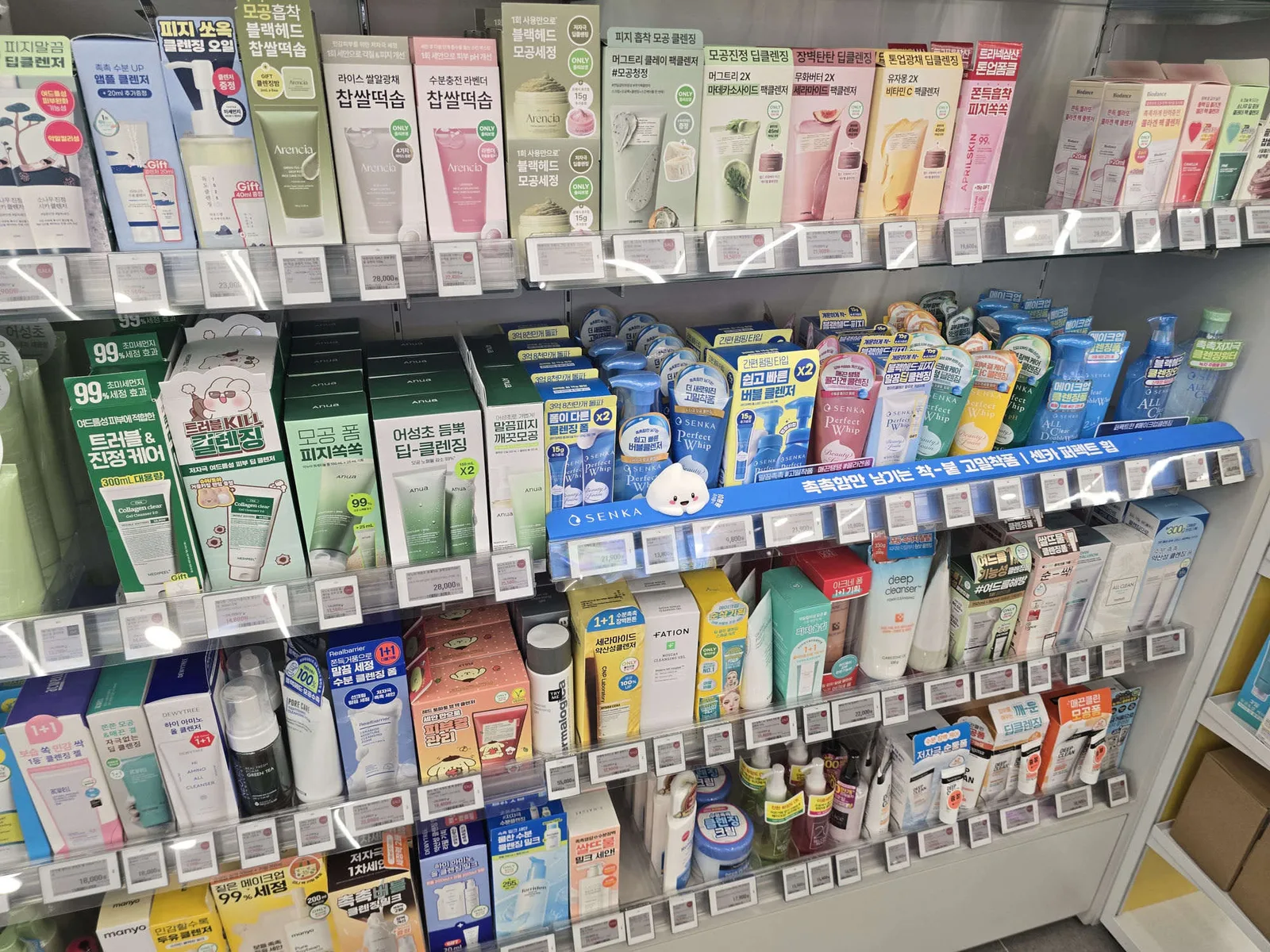 A close shelf view of many competing cleanser brands side by side at Olive Young