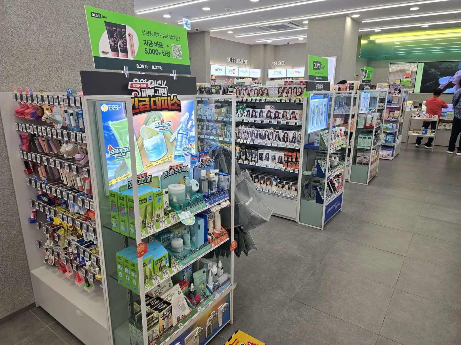 A recurring monthly sale sign inside an Olive Young store, above a skincare display