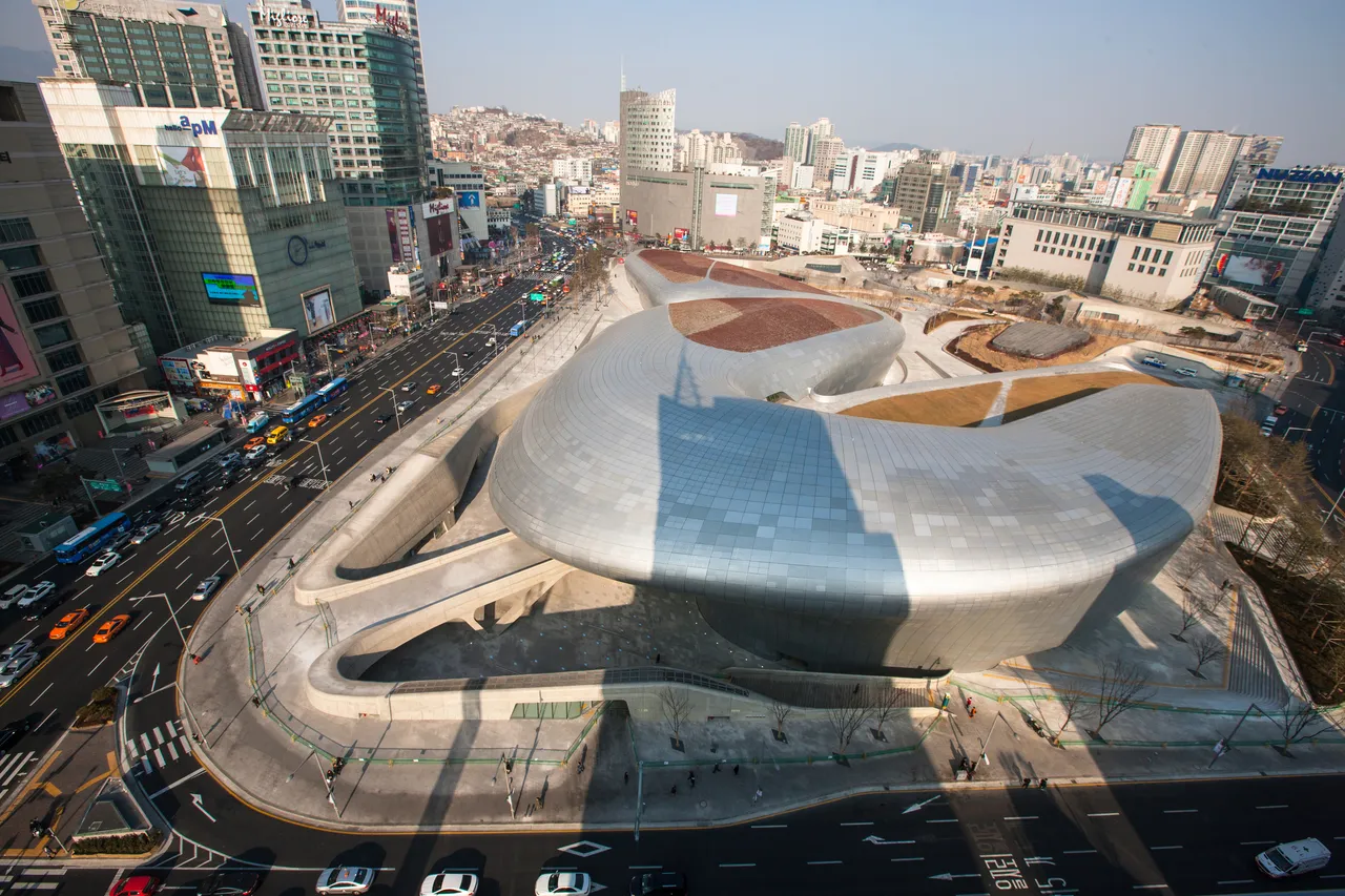 The curved silver form of the Dongdaemun Design Plaza seen from above on a clear day