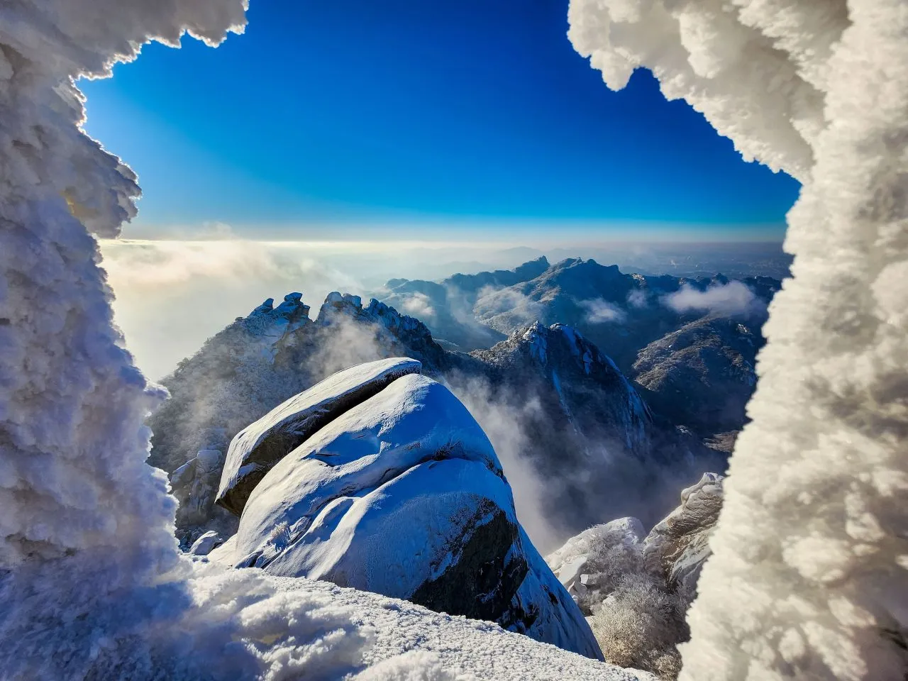 A granite ridge in Bukhansan National Park covered in snow and rime, with frosted pines and a blue sky