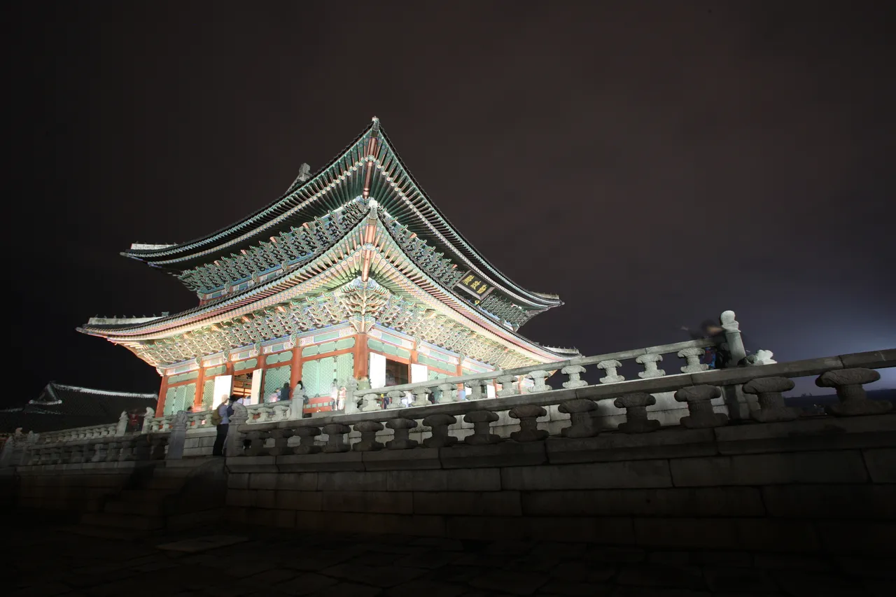 Gyeongbokgung Palace throne hall lit at night beneath a dark sky in Seoul