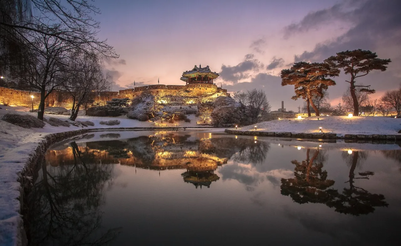 Banghwasuryujeong pavilion and stone fortress walls above Yongyeon Pond in Suwon at dusk