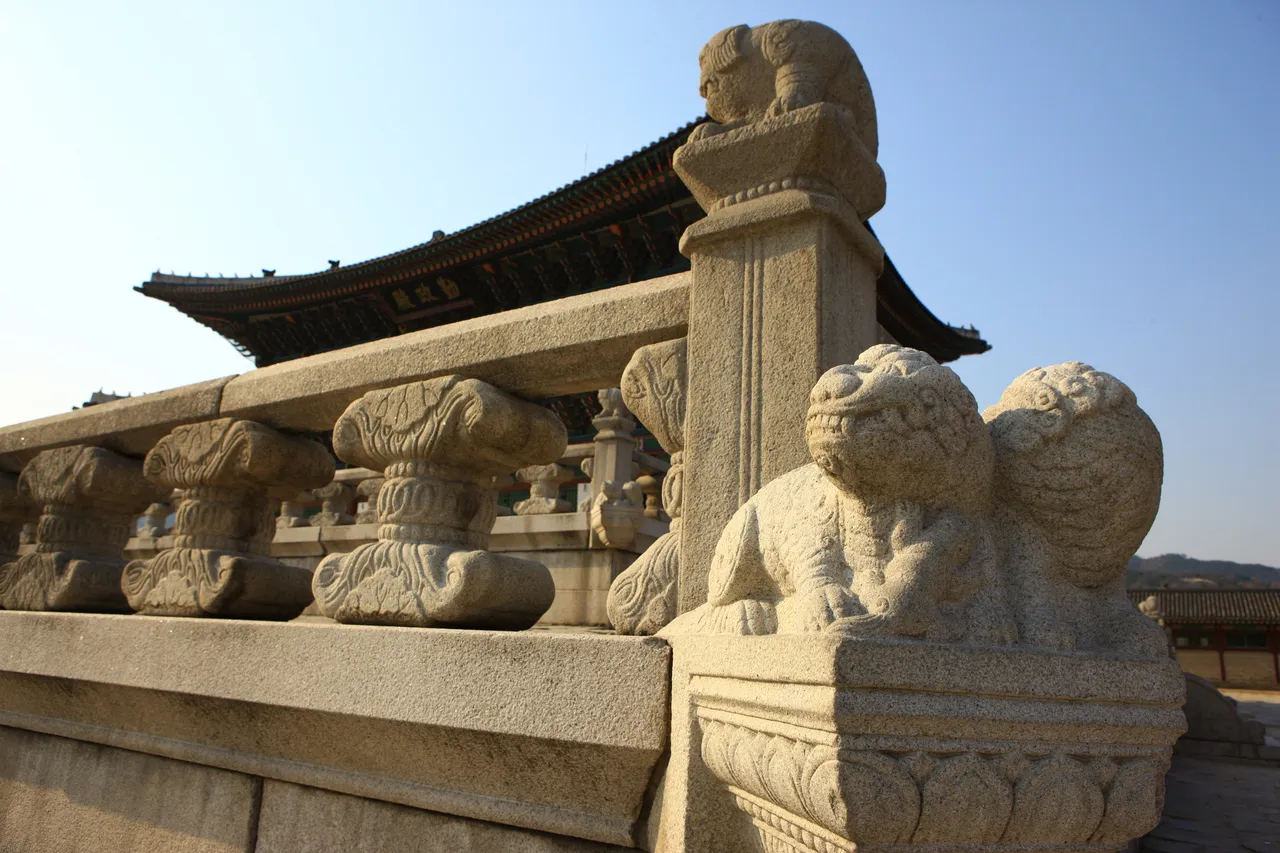 Stone guardian sculptures along a palace balustrade with a tiled palace hall behind