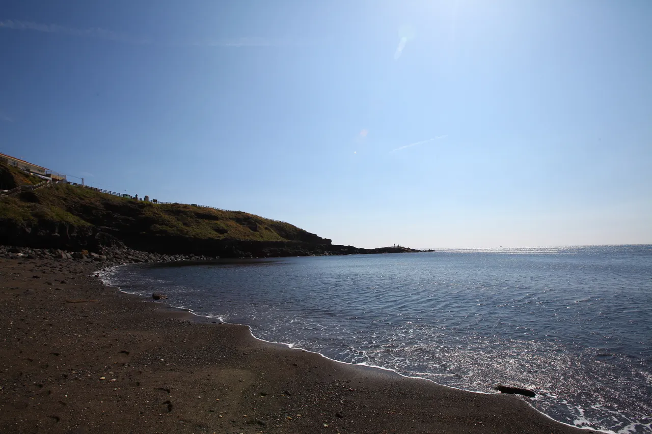 Dark volcanic sand and calm water on Geommeolle Beach on Udo's south shore