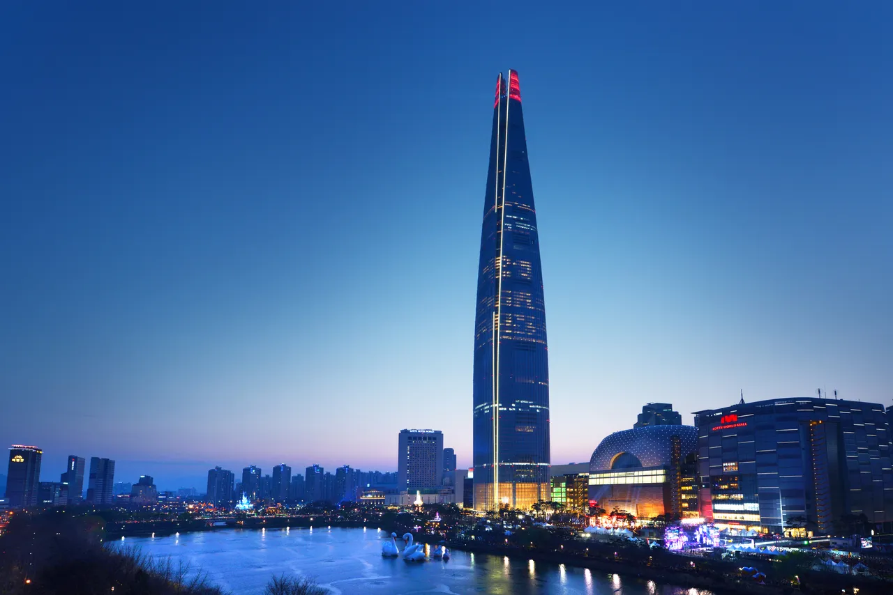 Lotte World Tower lit at dusk above the mall and Seokchon Lake in Jamsil, Seoul