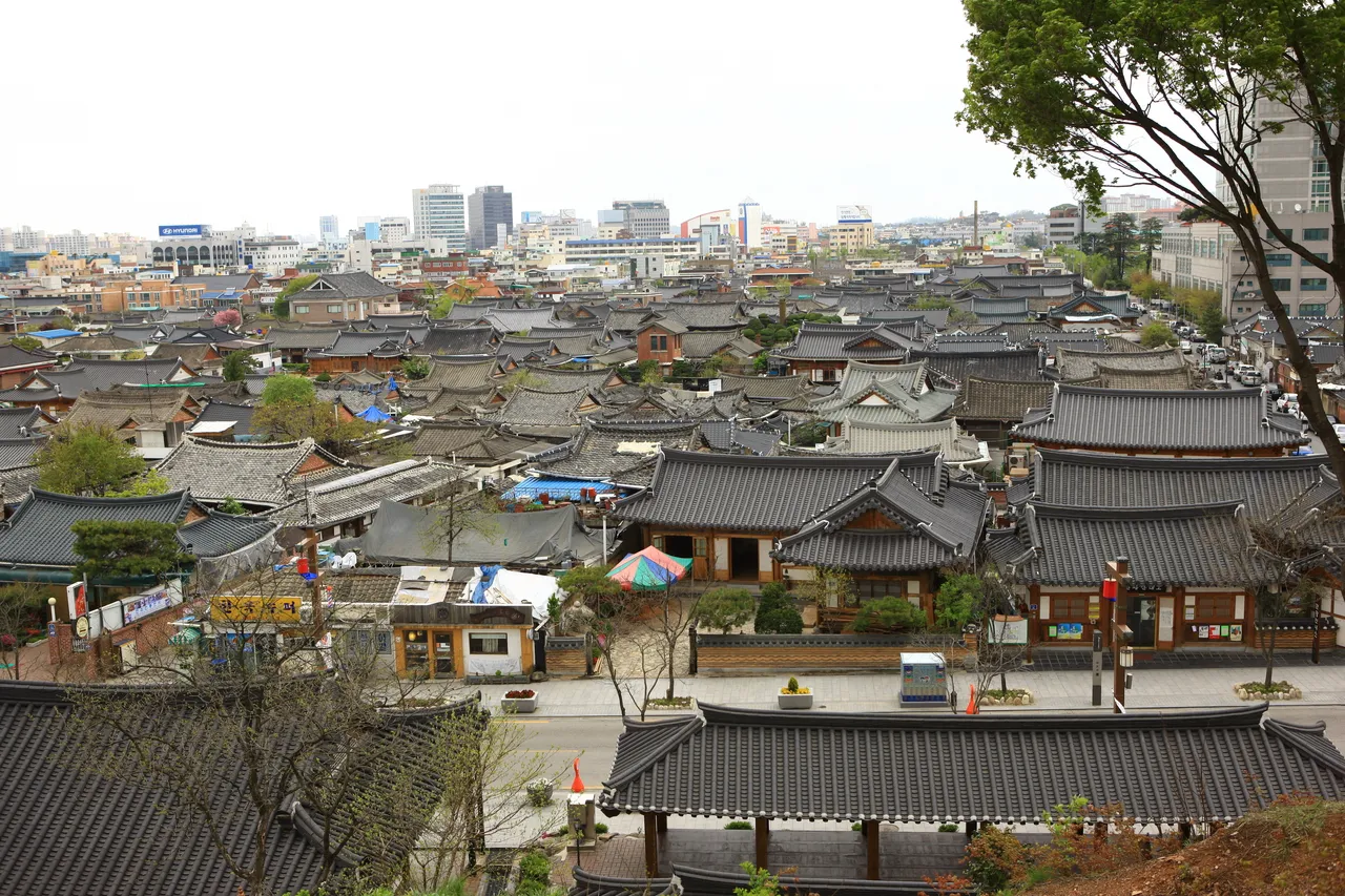 A panorama of the tiled rooftops of Jeonju Hanok Village with the modern city behind