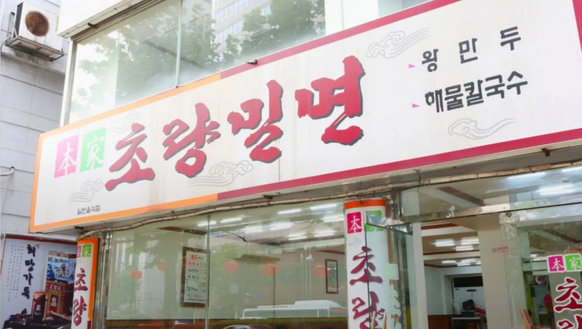 Storefront sign reading Choryang Milmyeon with dumpling and seafood noodle soup listed beside it
